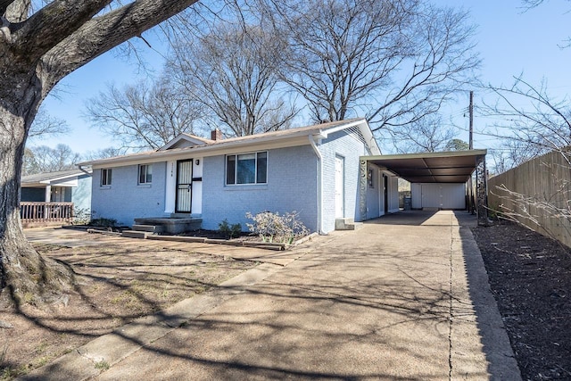 view of front facade with an attached carport, fence, driveway, a chimney, and brick siding