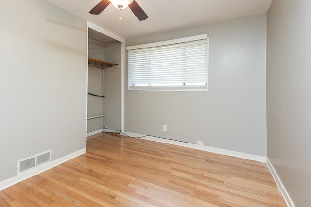 empty room featuring visible vents, a ceiling fan, baseboards, and wood finished floors