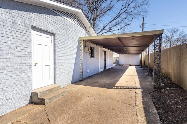 exterior space featuring an attached carport, entry steps, concrete driveway, and fence