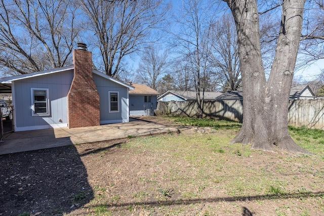 back of property featuring a patio area, a chimney, and fence