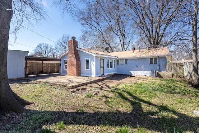 back of property with a patio area, a chimney, central AC, and fence