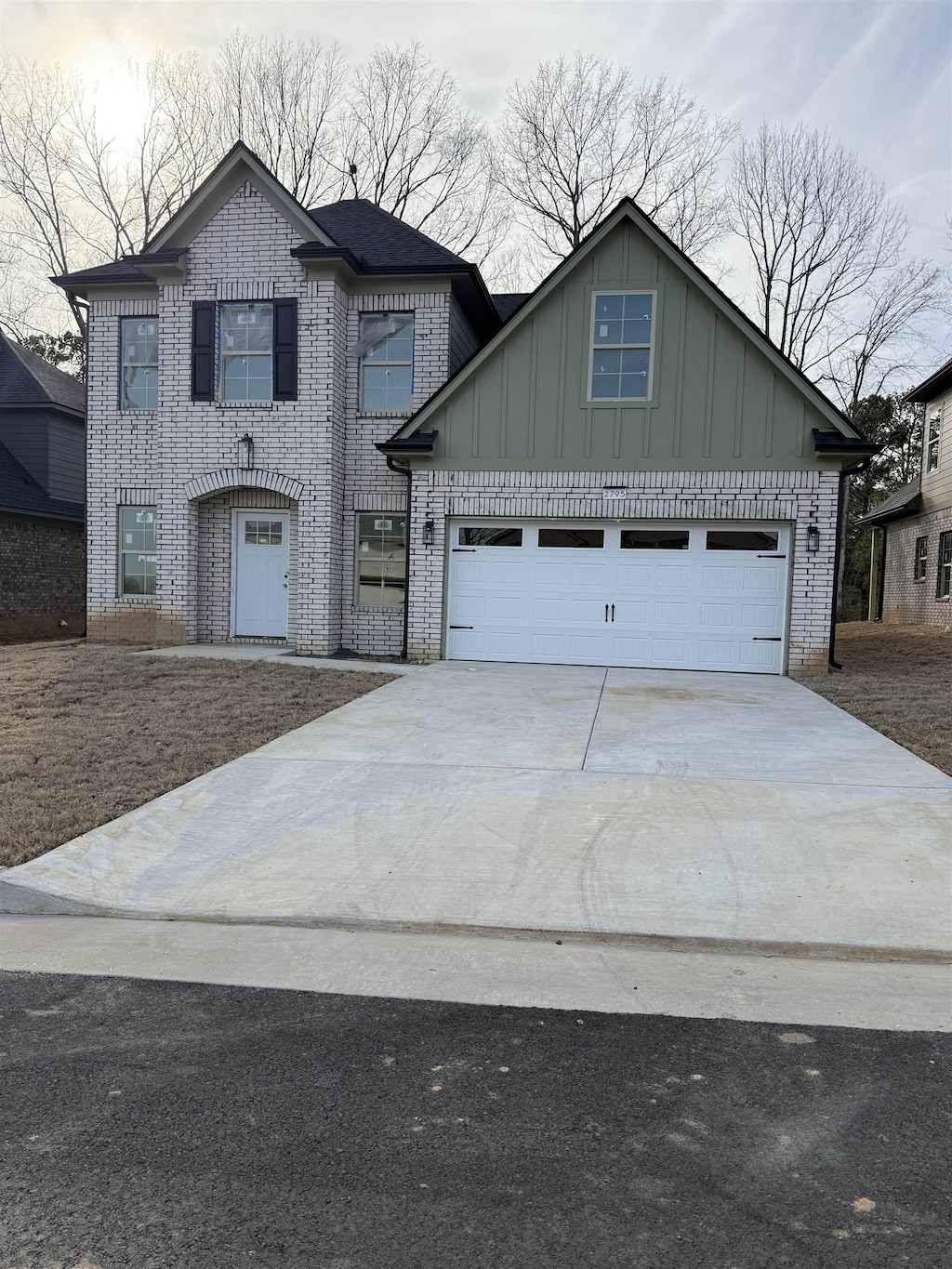 view of front of house featuring brick siding, board and batten siding, concrete driveway, and a garage