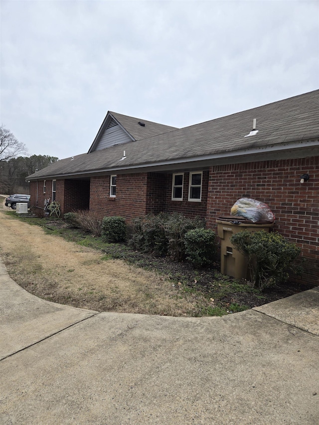 view of side of property featuring brick siding and a shingled roof