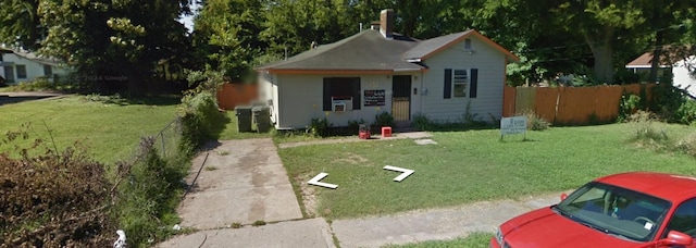 bungalow-style home with a front lawn and fence