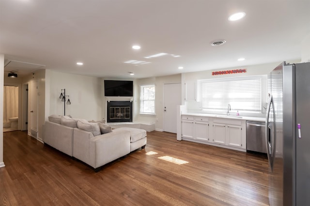 unfurnished living room with a glass covered fireplace, visible vents, wood finished floors, and recessed lighting