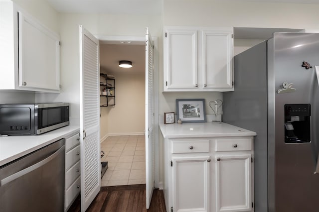 kitchen with white cabinets, stainless steel appliances, light countertops, and dark tile patterned flooring