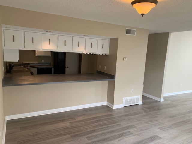 kitchen with visible vents, white cabinets, built in desk, and wood finished floors