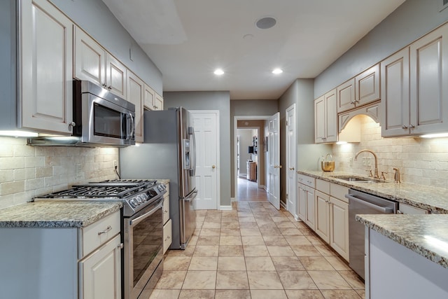 kitchen with baseboards, decorative backsplash, recessed lighting, appliances with stainless steel finishes, and a sink