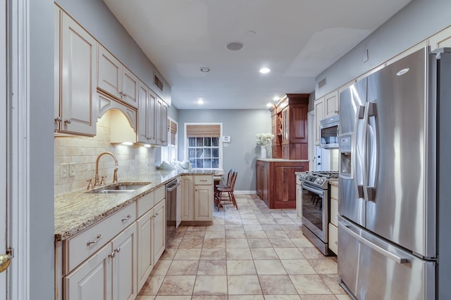 kitchen with visible vents, backsplash, light stone countertops, appliances with stainless steel finishes, and a sink