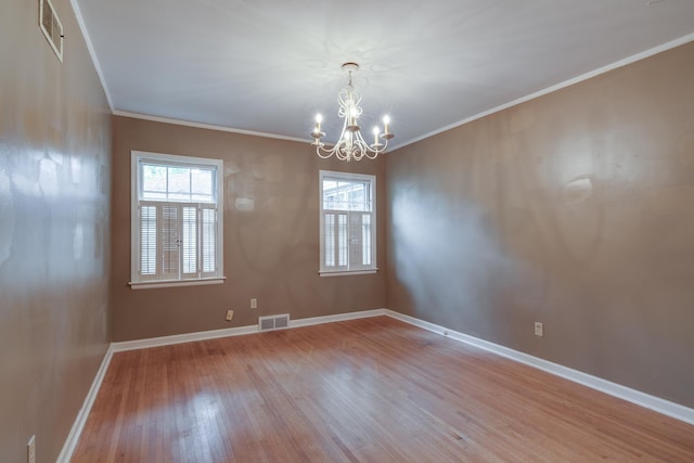 unfurnished room with visible vents, ornamental molding, baseboards, and wood finished floors