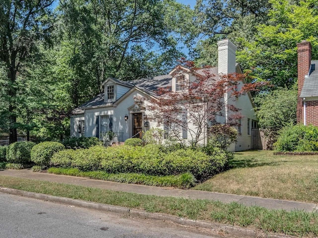 view of front of house featuring a chimney and a front yard