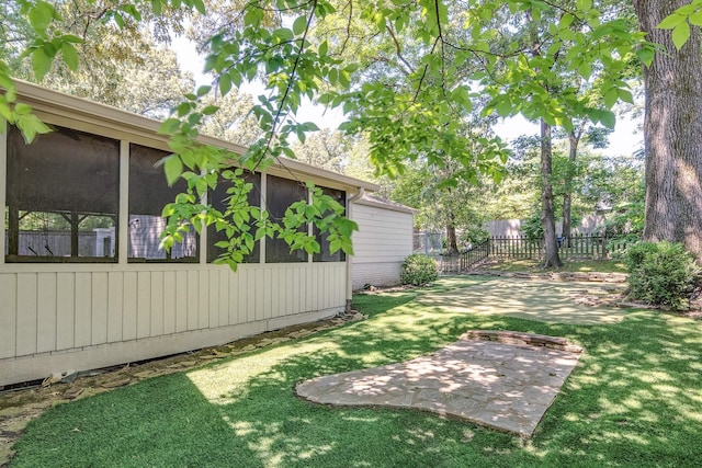 view of yard with a patio, fence, and a sunroom