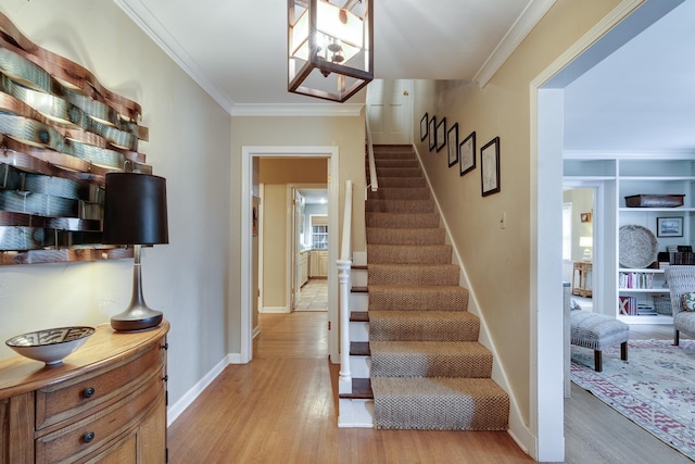 staircase featuring crown molding, wood finished floors, and baseboards