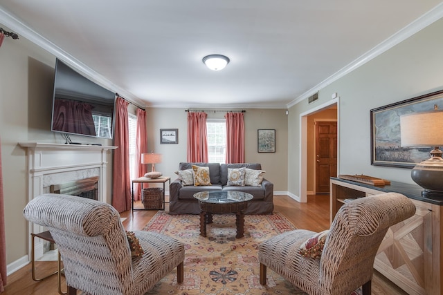 living room featuring visible vents, crown molding, baseboards, a fireplace, and wood finished floors