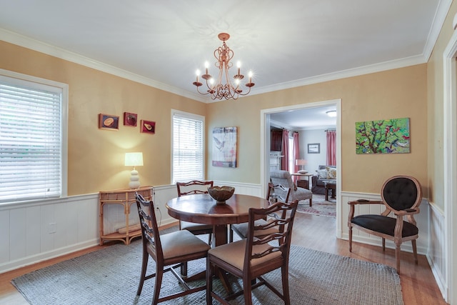 dining room with a wainscoted wall, light wood-style floors, and ornamental molding