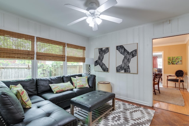 living room featuring a decorative wall, ceiling fan, and ornamental molding