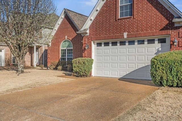 view of front of home with brick siding, concrete driveway, an attached garage, and a shingled roof