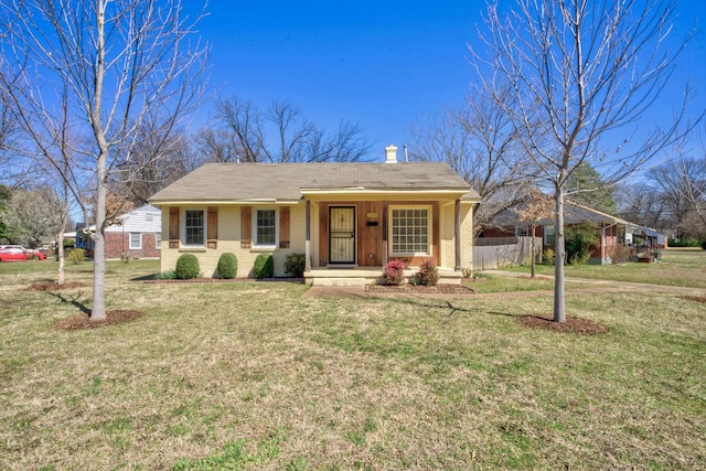 view of front of property with brick siding, fence, a porch, a front yard, and a chimney