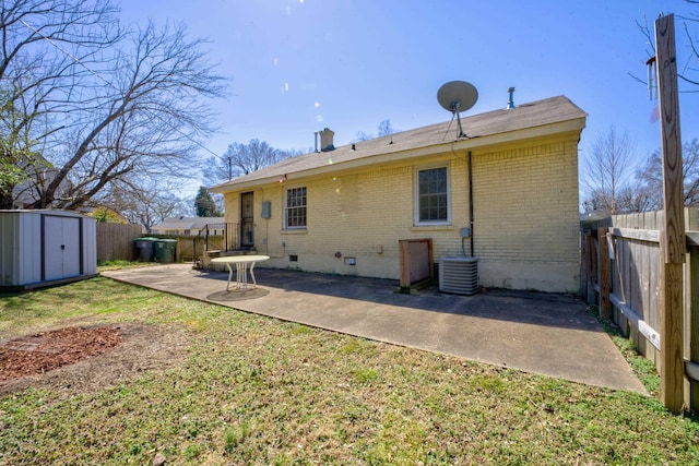 rear view of house with brick siding, a shed, crawl space, a patio area, and an outbuilding