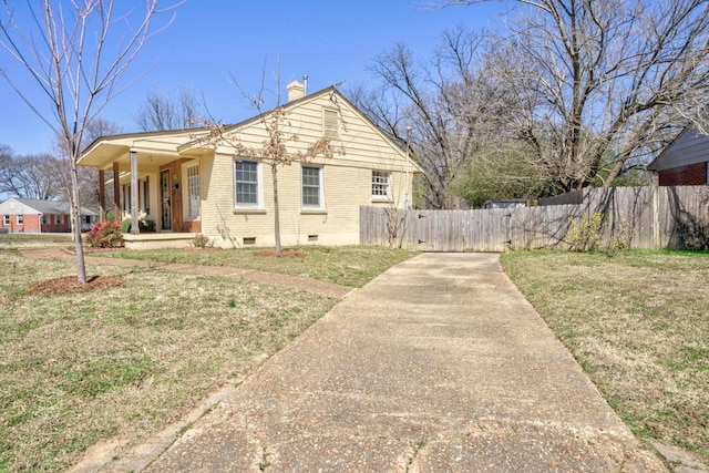 view of front of home featuring fence, covered porch, a chimney, a front lawn, and brick siding