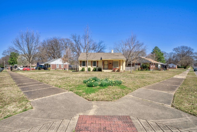 view of front of home with a chimney, a porch, a front yard, and fence