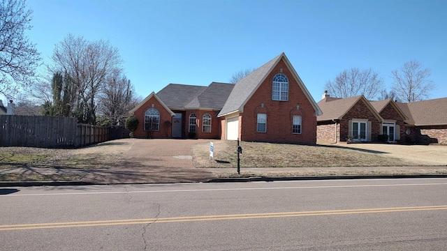 traditional-style home with fence, brick siding, and driveway