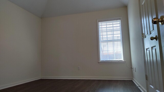 unfurnished room featuring lofted ceiling, baseboards, and dark wood-style flooring