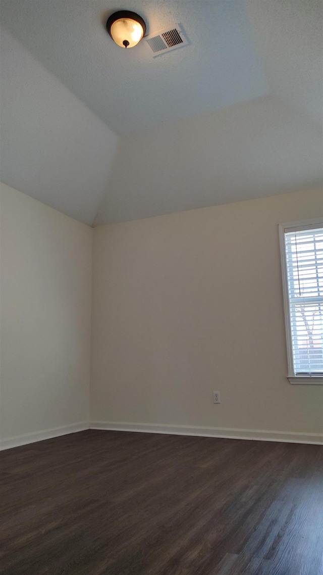 additional living space featuring visible vents, baseboards, dark wood-type flooring, and vaulted ceiling