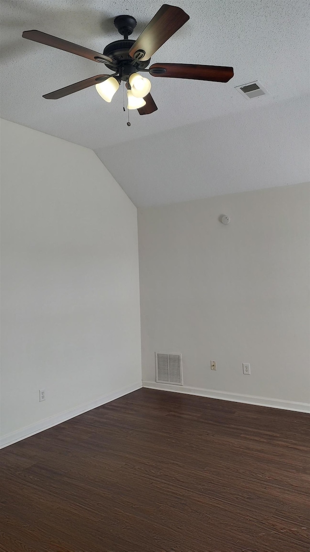 empty room with dark wood finished floors, lofted ceiling, visible vents, and a textured ceiling