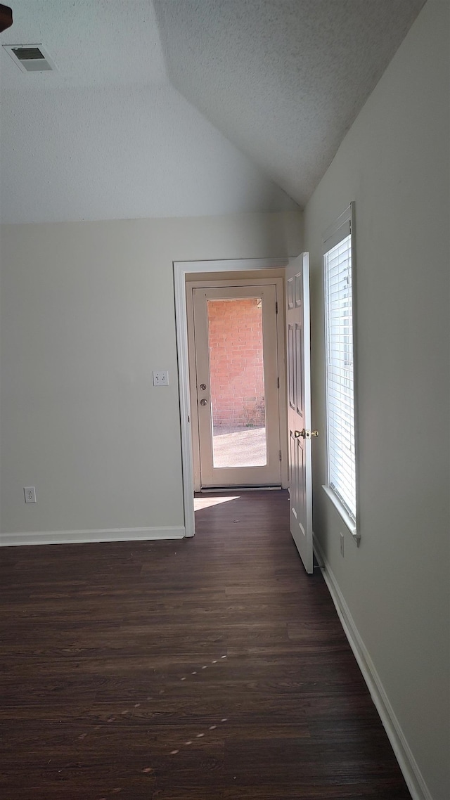 hall with visible vents, baseboards, lofted ceiling, and dark wood-style flooring