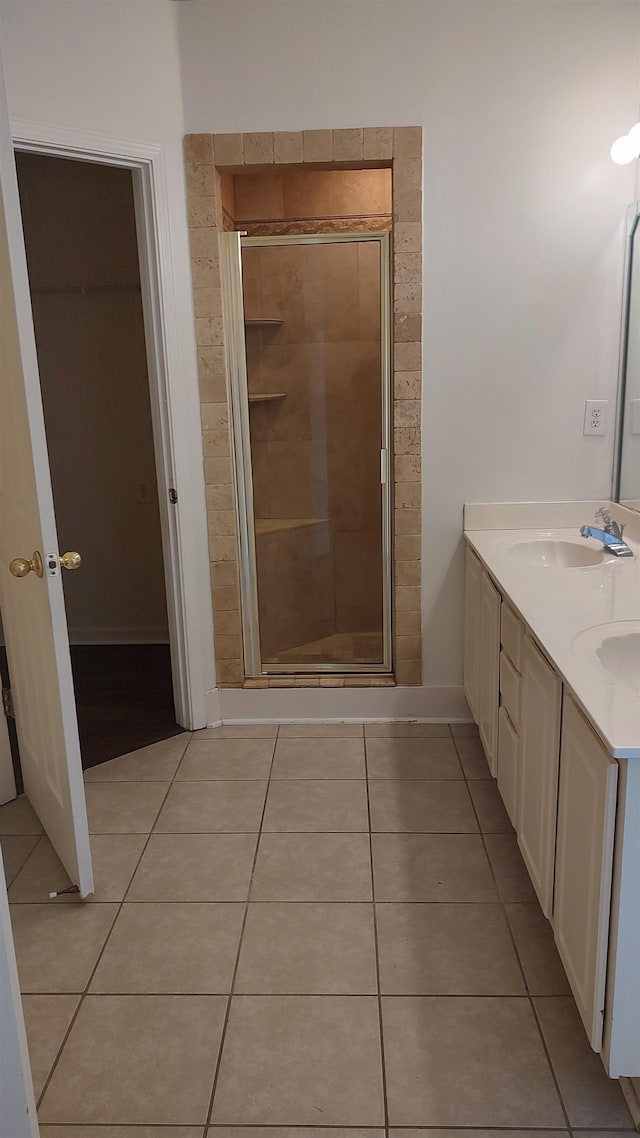 full bathroom featuring a sink, a stall shower, double vanity, and tile patterned flooring