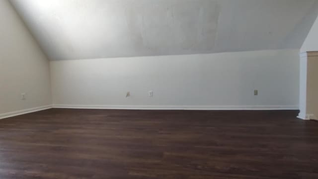 bonus room with lofted ceiling, baseboards, and dark wood-style flooring