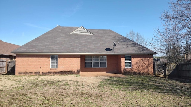 back of property featuring brick siding, a yard, and fence