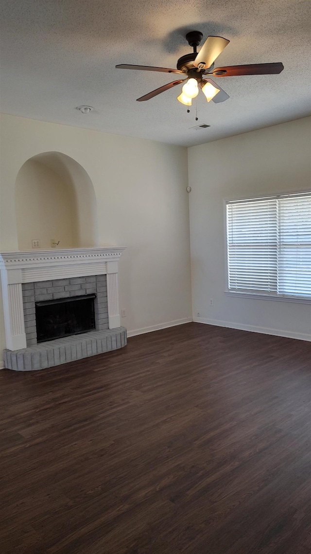 unfurnished living room with visible vents, a ceiling fan, a textured ceiling, a fireplace, and dark wood-style flooring