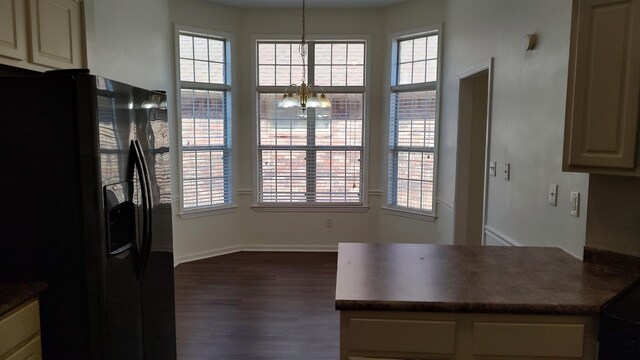 kitchen with dark countertops, a healthy amount of sunlight, and black refrigerator with ice dispenser