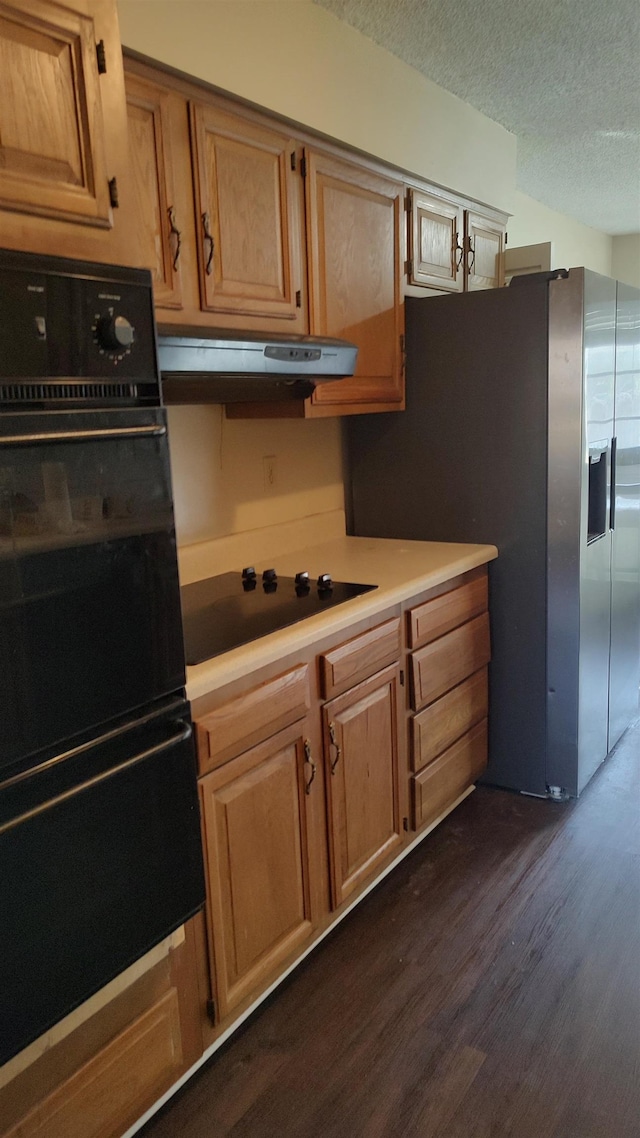 kitchen featuring range hood, dark wood-style flooring, black appliances, light countertops, and a textured ceiling