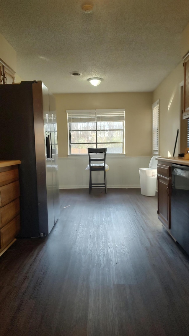 interior space featuring visible vents, dark wood finished floors, black dishwasher, a textured ceiling, and stainless steel fridge