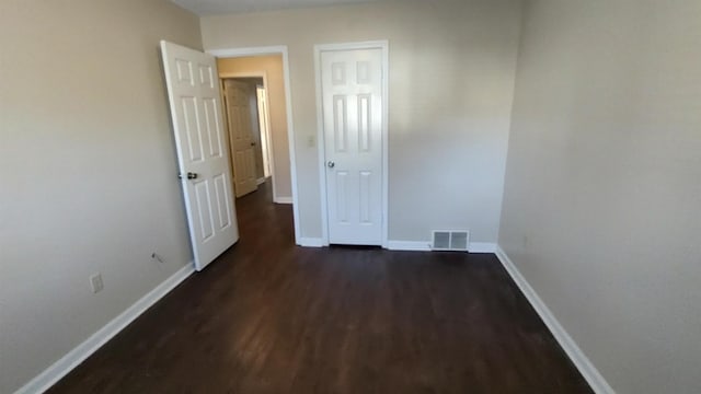 spare room featuring dark wood finished floors, visible vents, and baseboards