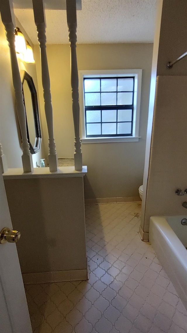 full bathroom featuring baseboards, toilet, vanity, shower / bathing tub combination, and a textured ceiling