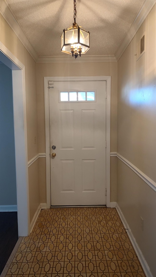 entryway featuring visible vents, a textured ceiling, baseboards, and ornamental molding