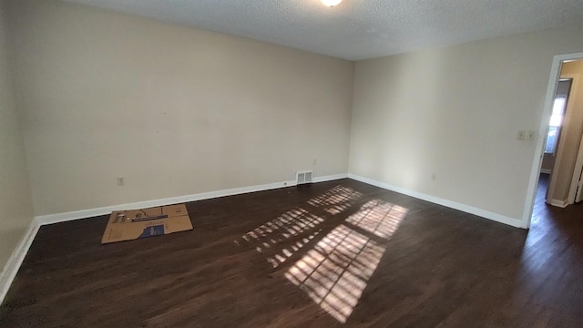 unfurnished room featuring visible vents, a textured ceiling, baseboards, and dark wood-style flooring