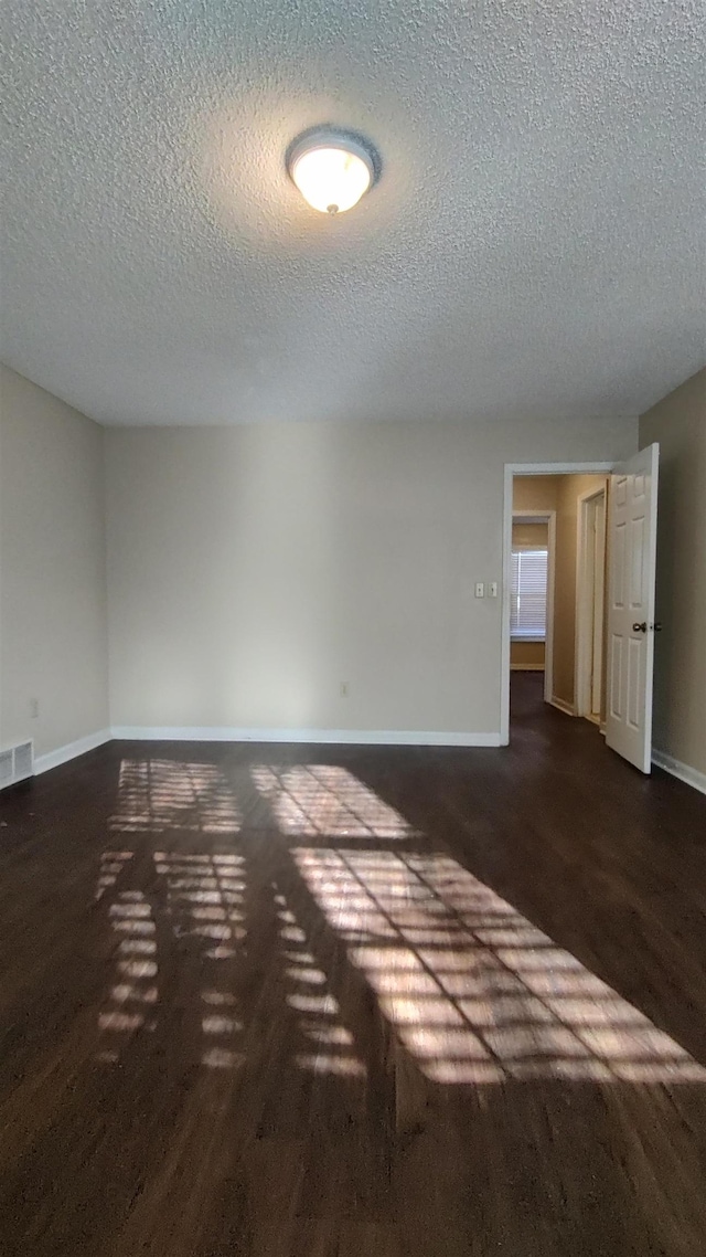 unfurnished room with visible vents, a textured ceiling, and baseboards