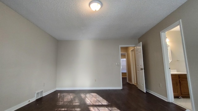 unfurnished bedroom featuring visible vents, baseboards, a textured ceiling, and wood finished floors