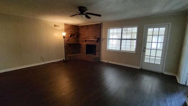 unfurnished living room featuring visible vents, dark wood-style floors, baseboards, a brick fireplace, and ceiling fan