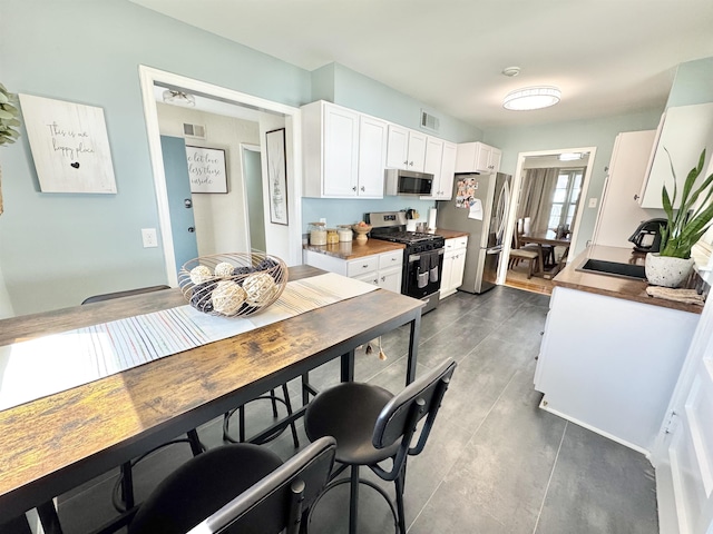 kitchen featuring a sink, visible vents, appliances with stainless steel finishes, and white cabinetry