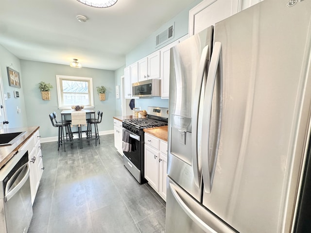 kitchen with stainless steel appliances, baseboards, visible vents, and white cabinets