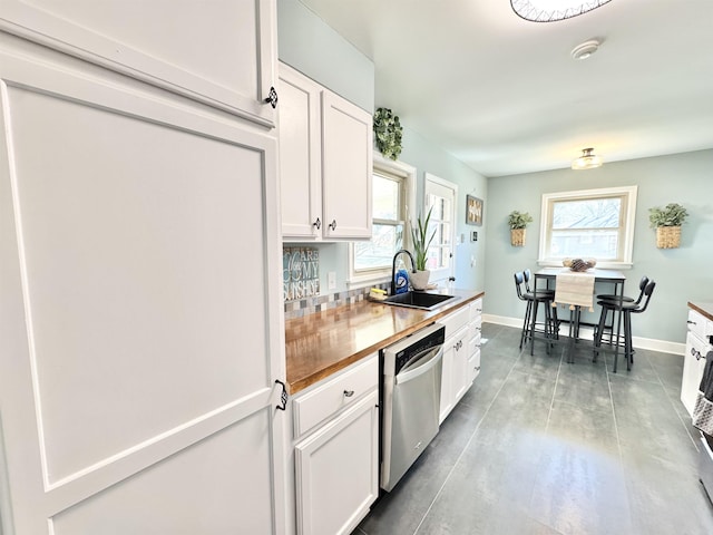 kitchen featuring a sink, white cabinetry, baseboards, and stainless steel dishwasher