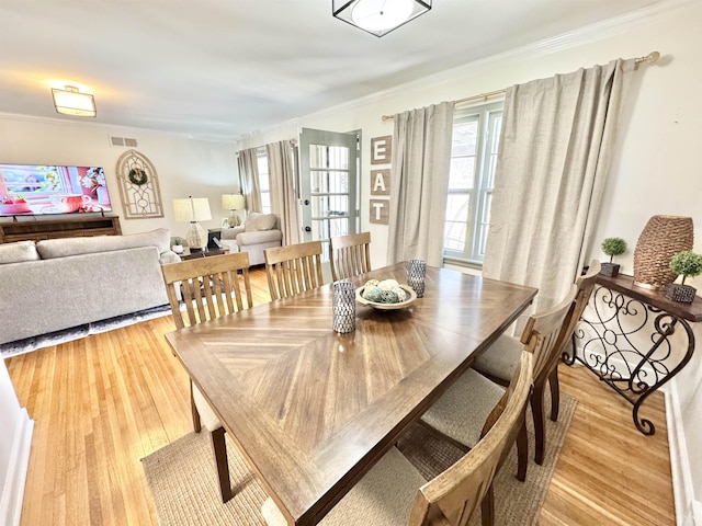 dining area with light wood-style flooring, visible vents, and a wealth of natural light