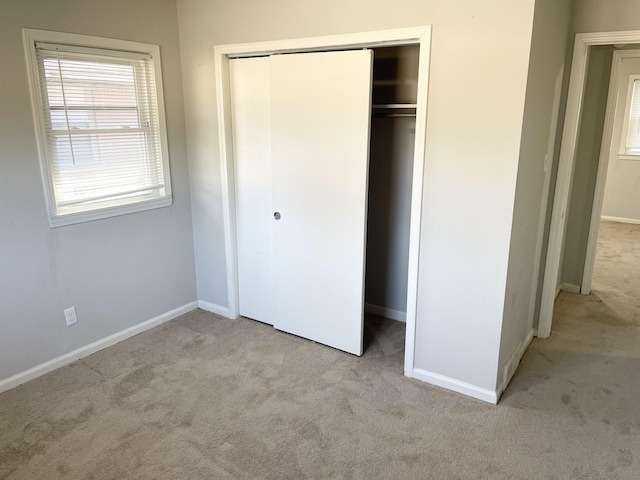 unfurnished bedroom with a closet, carpet floors, and baseboards