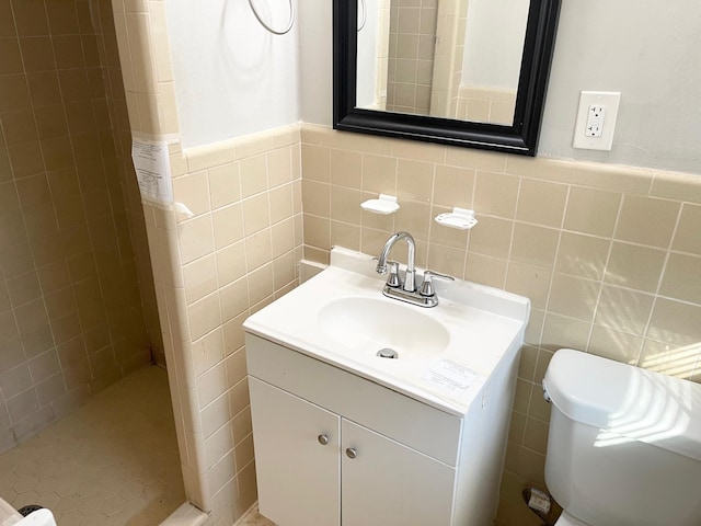 bathroom with vanity, tile walls, toilet, and a shower stall